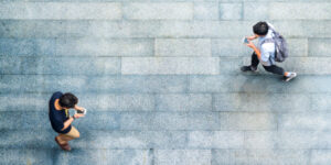 Aerial top view with blur man with smartphone walking converse with busy city crowd move to pedestrian crosswalk